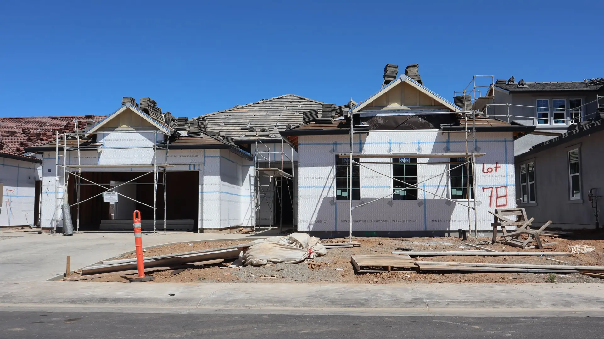 New house under construction with scaffolding and roofing materials on site
